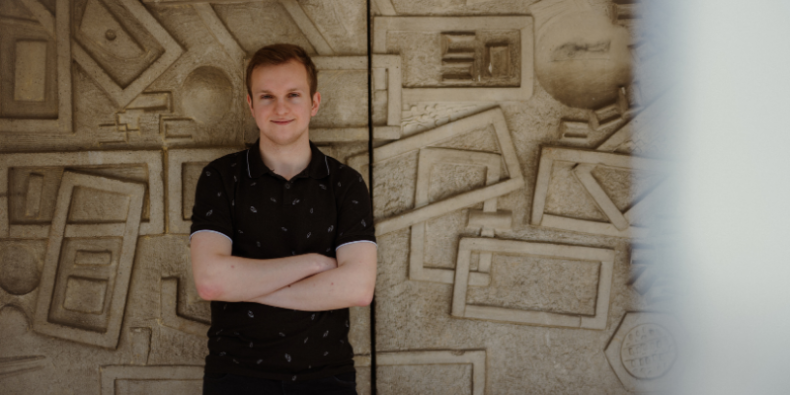 Maciej has his arms folded outside Derwent college